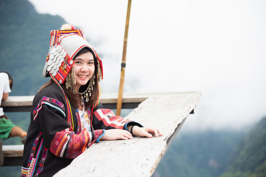 Mujer sonriente de Yunnan, parada frente a un paisaje en Yunnan